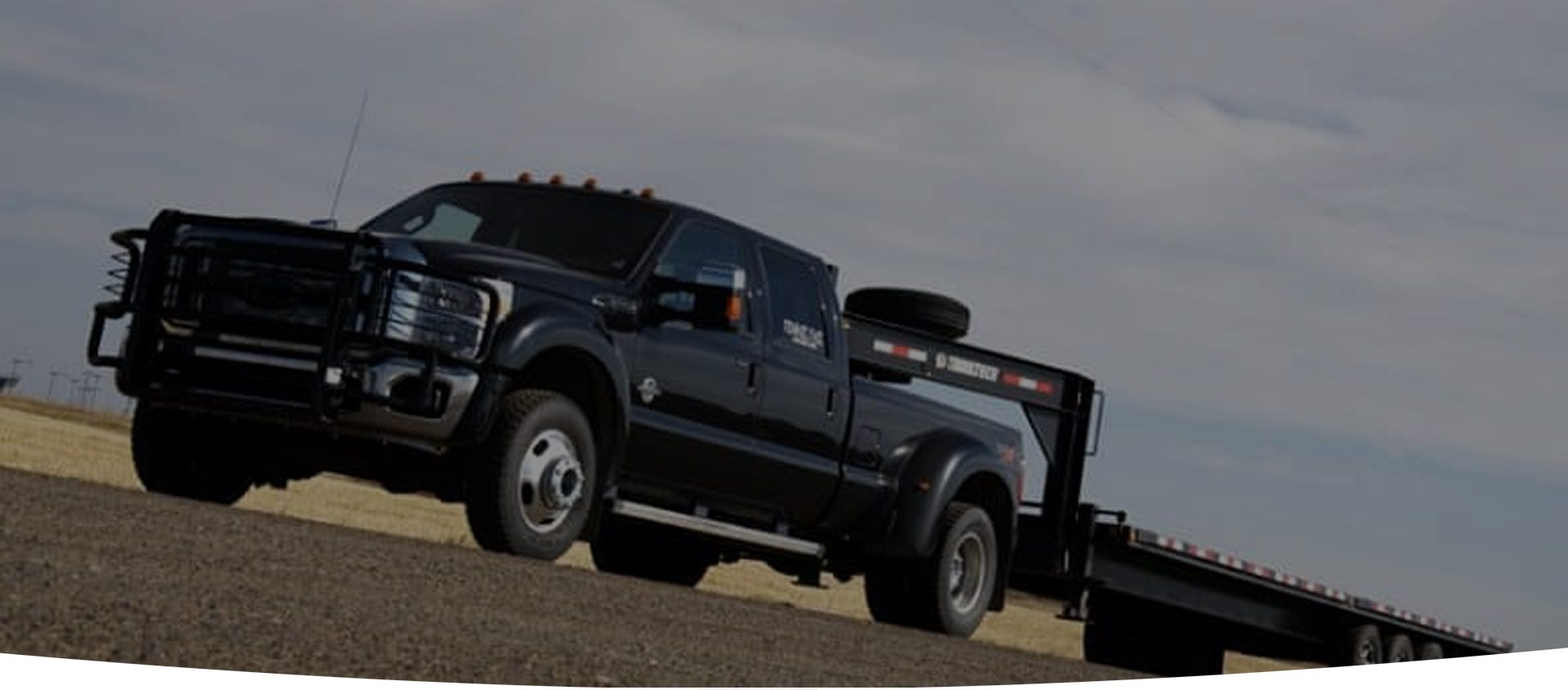 A black truck pulling a trailer on the road.